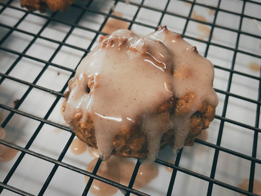 oatmeal peanut butter cookie sitting on a cooling rack with cinnamon vanilla icing dripping off