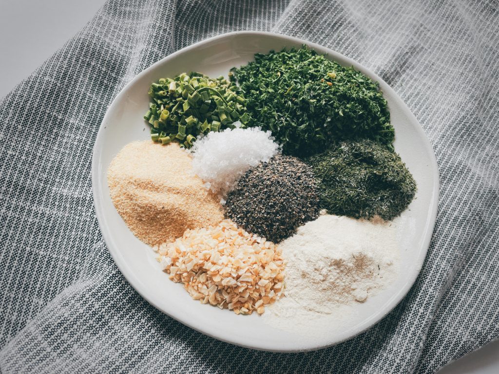 the ingredients to make homemade ranch seasoning on a small round plate sitting on top of a gray and white cloth napkin