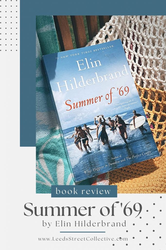 cover of Elin Hilderbrand's book Summer of 69, laying on top of a white and yellow crocheted beach bag and teal and white beach towel