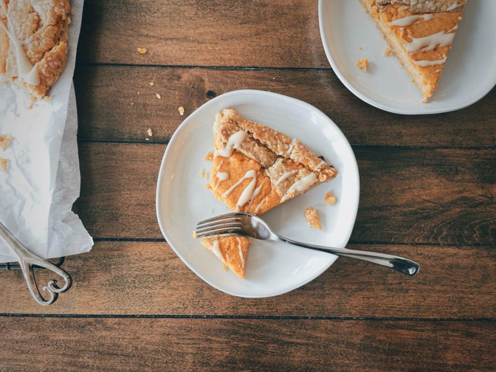 photo of a single slice of sweet potato galette on a round white plate with a fork